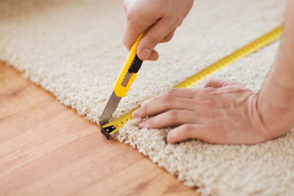 measuring and cutting new carpet for room